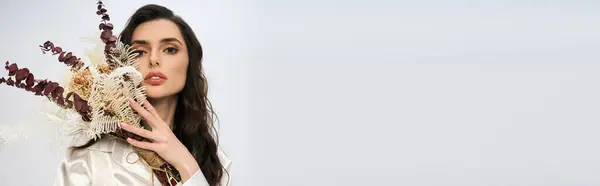 Una joven con cabello castaño posa elegantemente con flores, irradiando alegría y belleza, estandarte — Stock Photo