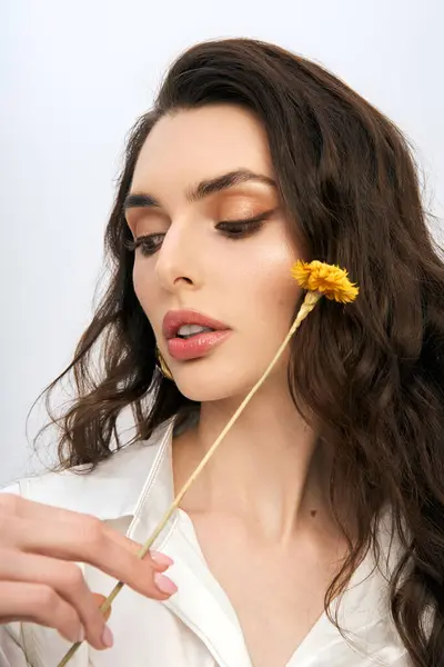 A young woman gracefully interacts with a flower, embodying the essence of spring beauty. — Stock Photo