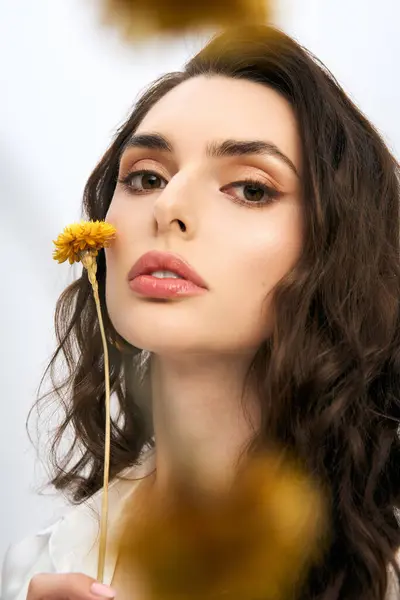 A lovely young woman poses gracefully holding yellow blooming flower — Stock Photo