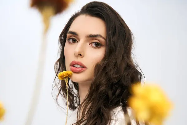 A young woman with brown hair poses among blooming flowers, embodying spring beauty. — Stock Photo