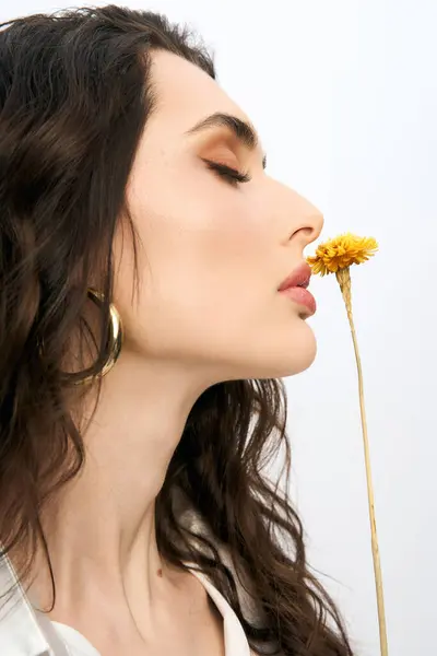 A young woman with beautiful brown hair gently interacts with vibrant flower in spring. — Stock Photo