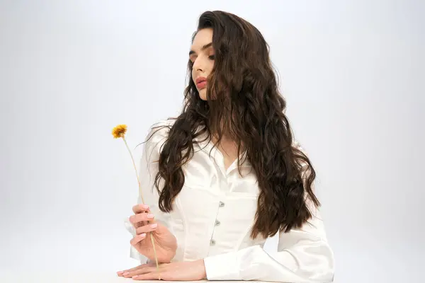 Young woman with beautiful brown hair embraces the essence of spring with vibrant flower — Stock Photo