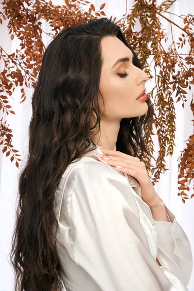 A beautiful young woman with brown hair stands gracefully among colorful leaves, embracing spring. — Stock Photo
