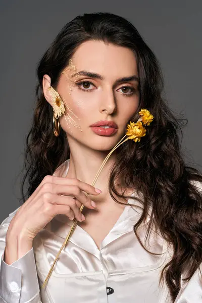 A young woman showcases her beauty with brown hair, holding flowers in a spring-inspired setting. — Stock Photo