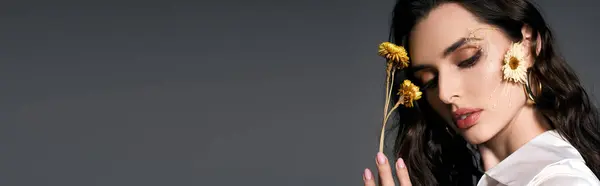 Une jeune femme aux cheveux bruns tient doucement des fleurs, incarnant l'essence du charme du printemps, bannière — Photo de stock