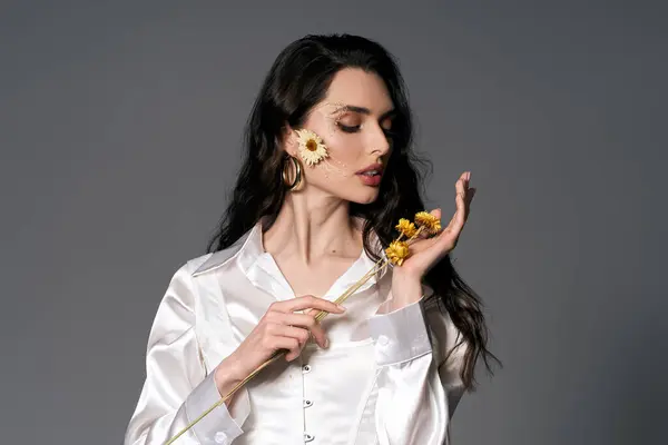 A young woman with brown hair enjoys the beauty of spring flowers in a studio. — Stock Photo