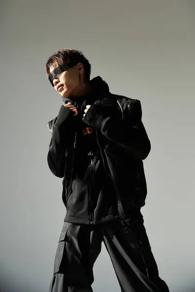 A stylish Asian man poses confidently in a sleek urban outfit. — Stock Photo