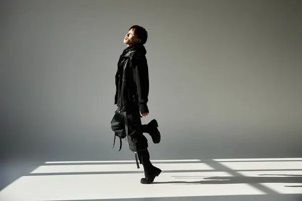 A young, handsome Asian man poses confidently in stylish black against a minimal backdrop. — Stock Photo
