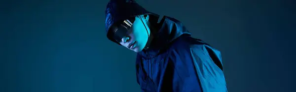 A young handsome man poses confidently in a stylish outfit, illuminated by blue light in a studio. — Stock Photo