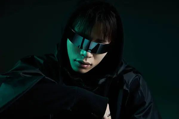 In a chic setting, a handsome young Asian man in black models unique sunglasses with style. — Stock Photo