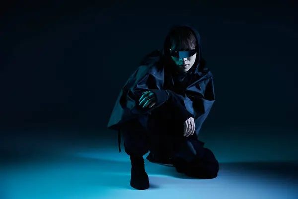 A stylish Asian man crouches confidently against a cool blue background. — Stock Photo