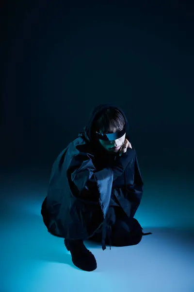 Un beau jeune homme asiatique est capturé dans une pose dynamique, entouré d'une lumière bleue vive. — Photo de stock