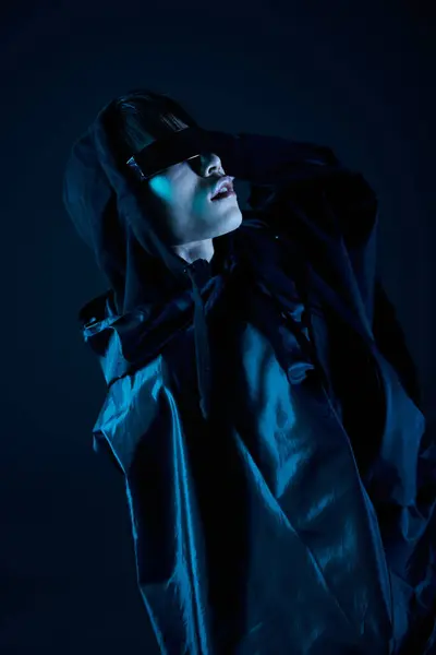 Handsome man in a stylish outfit poses dramatically under dim blue light, radiating confidence. — Stock Photo