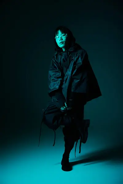 A handsome young man in sleek attire stands confidently in an artistic blue lit environment. — Stock Photo