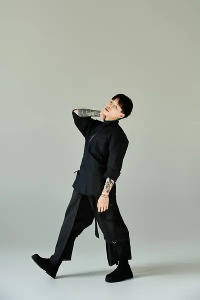 Un joven tatuado toma una pose elegante en un entorno sencillo. - foto de stock