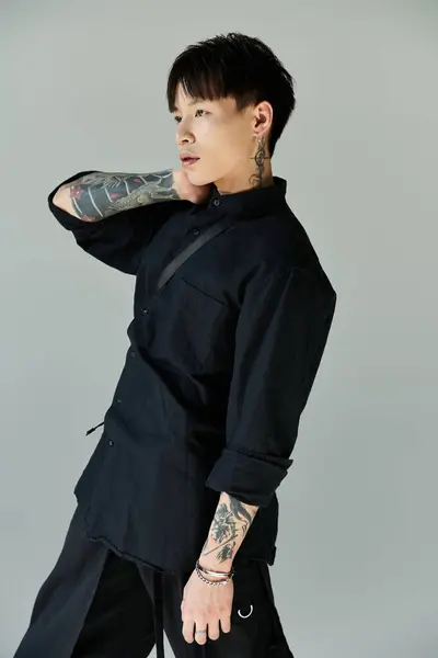 A stylish young Asian man with tattoos poses confidently indoors. — Stock Photo