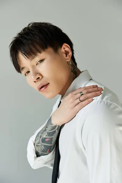 Handsome young man poses confidently in a stylish outfit, highlighting his tattoos and accessories. — Stock Photo