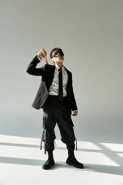 Young asian man wearing a suit strikes a confident pose while holding a stylish accessory. — Stock Photo