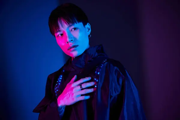 Handsome young man stands confidently, showcasing his unique style in bold, colorful lighting. — Stock Photo