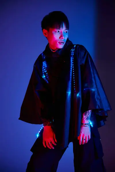 A stylish young man confidently displays his outfit, lit by vibrant colorful lights. — Stock Photo