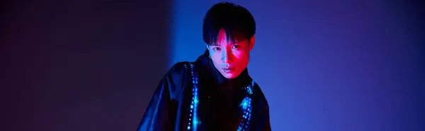 A handsome asian man showcases his unique style with vibrant lighting in an artistic setting. — Stock Photo