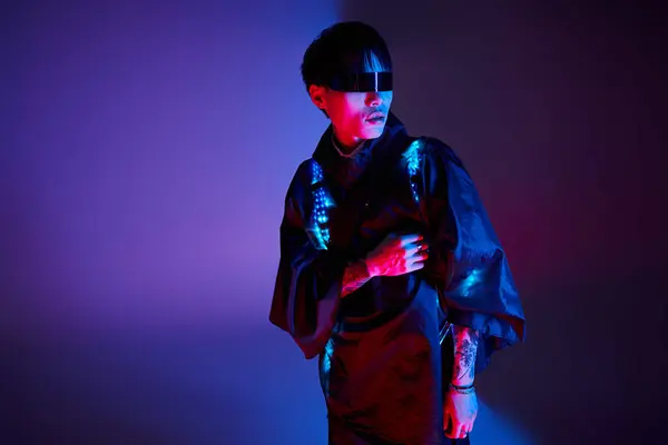 Young Asian man showcases a blend of traditional and modern style under colorful lights. — Stock Photo