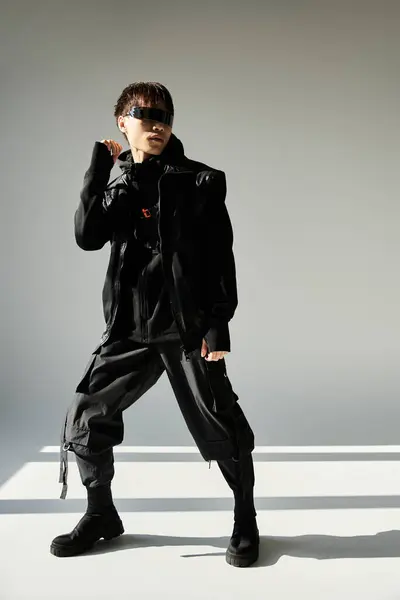 A stylish young Asian man poses confidently in a modern, minimal space in black attire. — Stock Photo