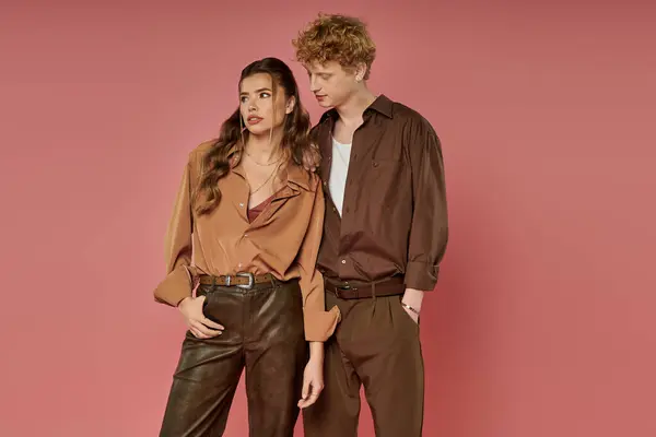 A stylish couple shares a sweet moment in vibrant outfits against a soft pink backdrop. — Stock Photo