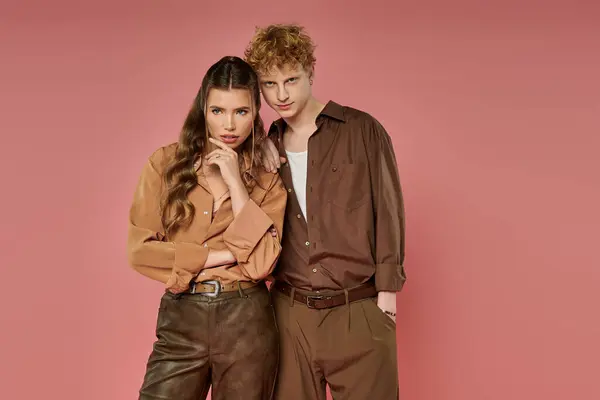 Young couple poses in modern attire, showcasing their love against a pink backdrop. — Stock Photo