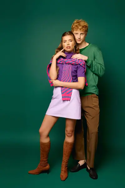 Pareja joven en trajes vibrantes se abraza, irradiando amor y confianza en la moda. - foto de stock