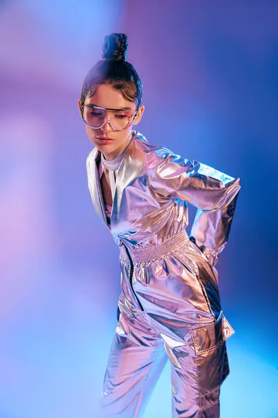 A young woman in metallic wear displays modern fashion with holographic hues in a vibrant scene. — Stock Photo
