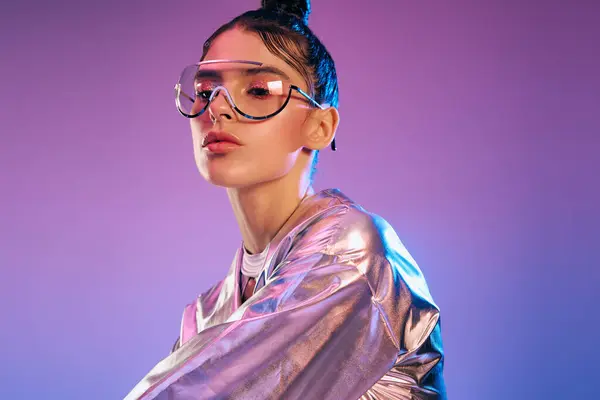 Mujer con estilo presenta traje holográfico experimental contra un telón de fondo colorido. - foto de stock