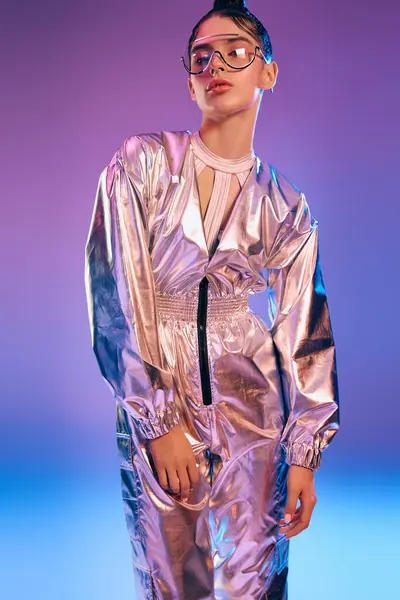 A young woman showcases her beauty in a chic metallic outfit illuminated by holographic colors. — Stock Photo