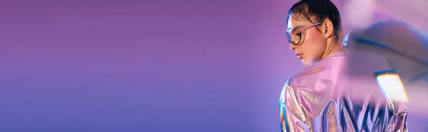 Young woman showcases modern holographic attire while exuding confidence in a colorful environment. — Stock Photo