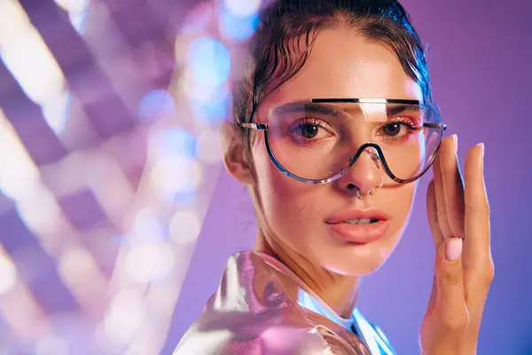 A stylish woman showcases futuristic attire with holographic colors against a vibrant backdrop. — Stock Photo