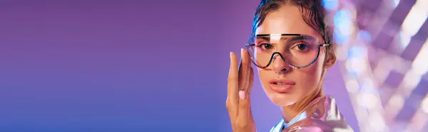 A young woman confidently displays her holographic outfit against a backdrop of vibrant colors. — Stock Photo