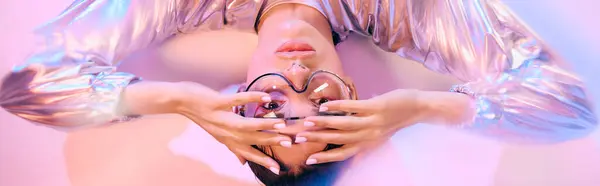 A vibrant young woman poses elegantly, showcasing futuristic fashion in holographic colors. — Stock Photo