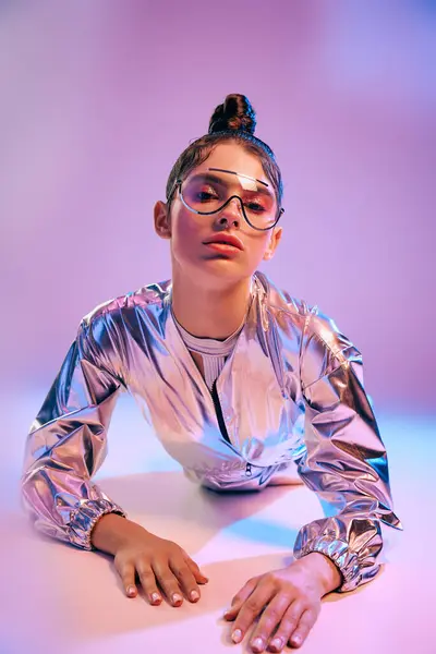 A young woman leans over a surface in a shiny holographic outfit amid vibrant colors. — Stock Photo