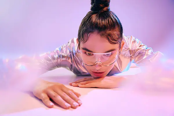 A young woman showcases her unique style in holographic attire while lying on a soft surface. — Stock Photo