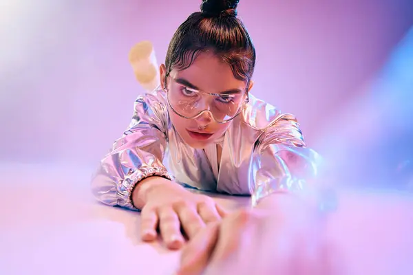 A young woman confidently showcases her holographic outfit in a creatively lit space. — Stock Photo