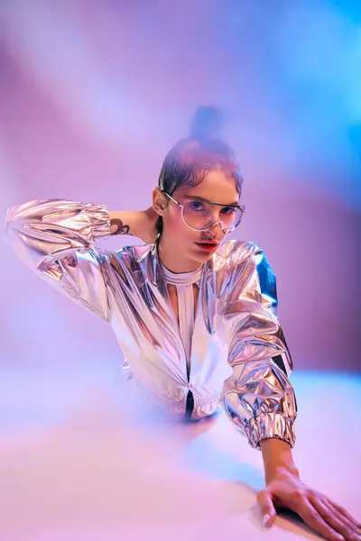 A stylish woman in holographic attire poses dynamically against a vibrant backdrop of colors. — Stock Photo
