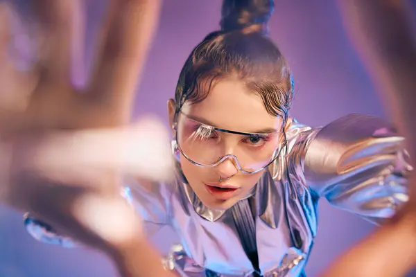 A young woman dazzles in holographic attire and stylish glasses in a vibrant, modern space. — Stock Photo