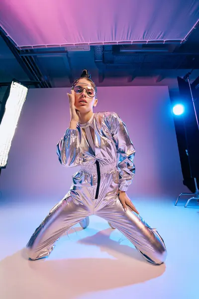 A young woman dazzles in holographic attire amid a vibrant, modern setting. — Stock Photo