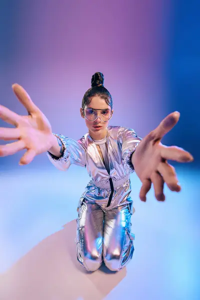 A stylish young woman in metallic fashion extends an inviting hand with a futuristic flair. — Stock Photo