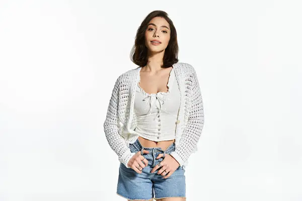 Una giovane donna elegante in abiti estivi alla moda posa elegantemente su uno sfondo luminoso. — Foto stock