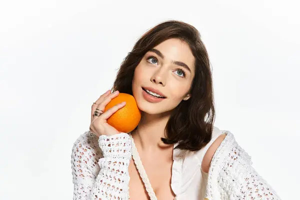 A stylish young woman radiates summer charm while playfully holding an orange, exuding joy. — Stock Photo