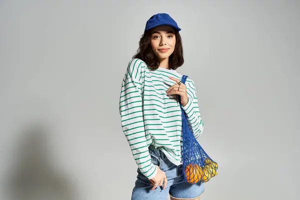 Une jeune femme modèle des vêtements d'été élégants avec un sac coloré de fruits. — Photo de stock