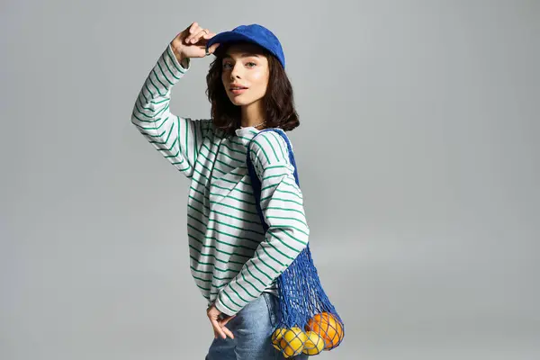 Brightly dressed woman poses with a mesh bag of fruit, radiating summer joy and confidence. — Stock Photo