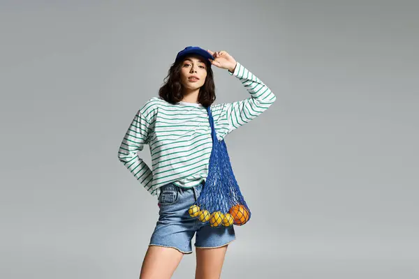 Une journée d'été lumineuse met en valeur une jeune femme confiante en tenue rayée tendance et un sac ludique. — Photo de stock