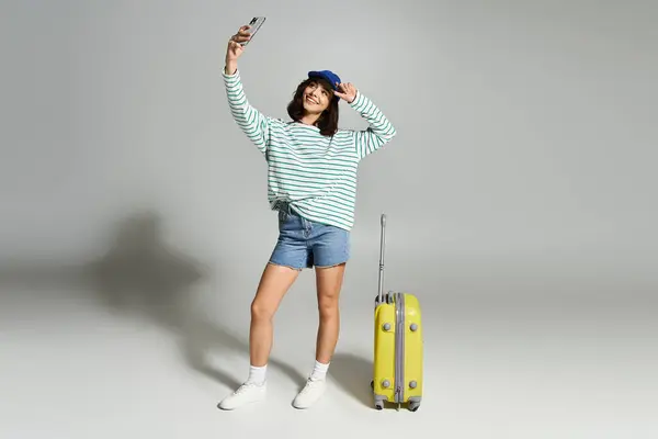 Une jeune femme en tenue estivale tendance capture un moment passionnant tout en posant avec sa valise. — Photo de stock